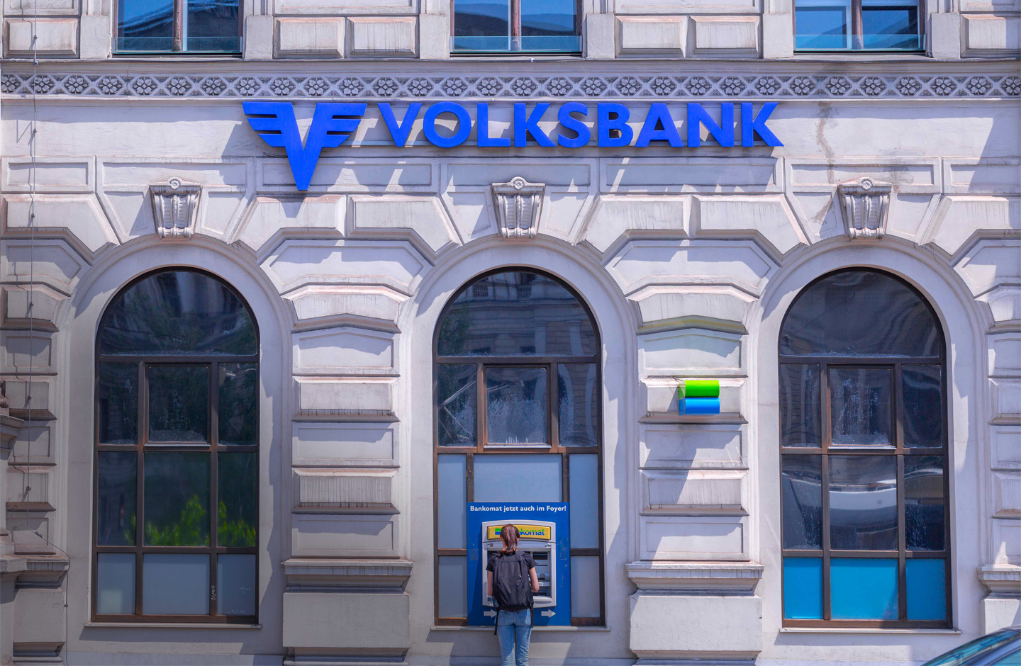 Die weiße Steinfassade einer Volksbank-Filiale bei Sonnenschein.
