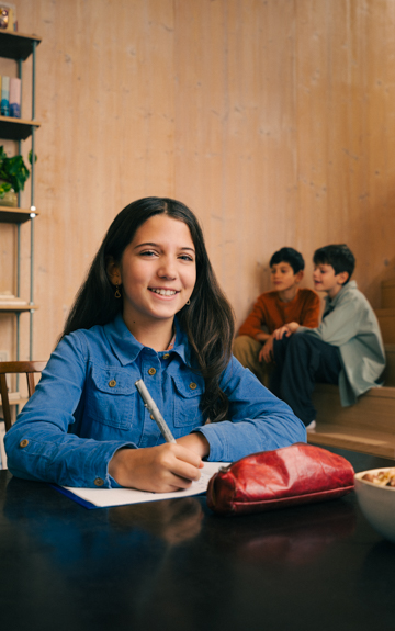 Ein Bub sitzt auf einem Tisch in der Küche und hält eine Volksbank Jugend Sparkarte in der Hand.